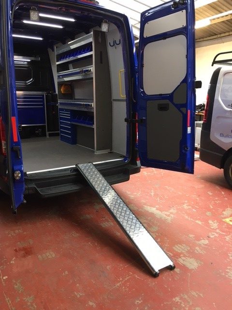 van showing metal shelving units installed inside and metal ramp leading up to van floor